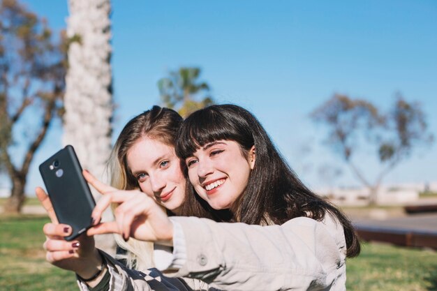 Ragazze luminose contenti che posano per selfie