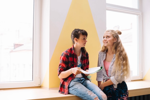 Ragazze sedute con il libro di testo