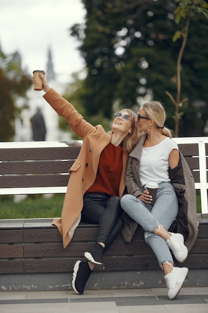 Ragazze sedute in primavera e tengono il caffè in mano