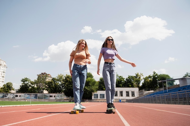 Ragazze sorridenti a tutto campo con penny board all'aperto