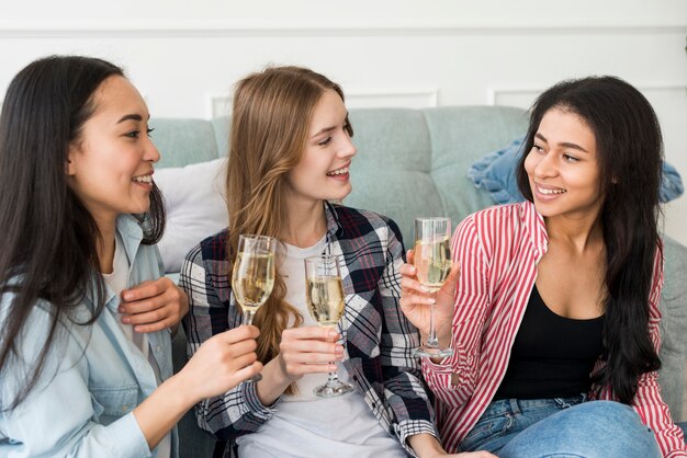 Ragazze sorridenti che si siedono e che tengono i vetri con la bevanda in mani