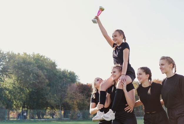 Ragazze sorridenti che vincono un trofeo