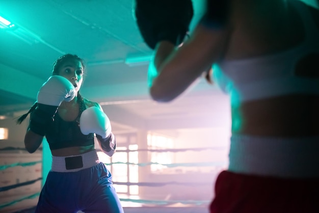 Ragazze sportive che si allenano a combattere sul ring. Due ragazze caucasiche in abbigliamento sportivo e guanti protettivi si allenano in palestra e si allenano a pugni. Boxe femminile, concetto di stile di vita sano