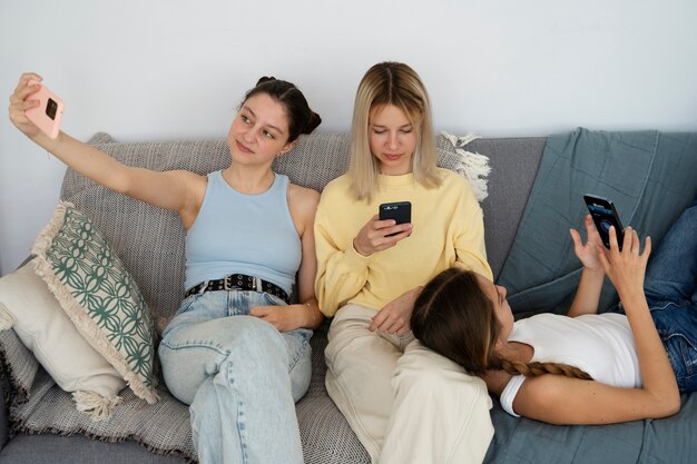 Ragazze sul divano con smartphone ad alto angolo