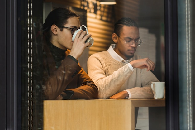 Ragazzi di tiro medio che bevono caffè al chiuso