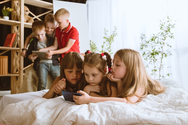 Ragazzi e ragazze che usano diversi gadget a casa