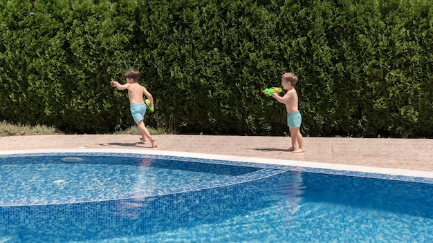 Ragazzi in piscina giocando con la pistola ad acqua