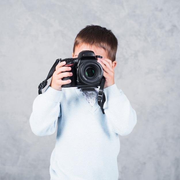 Ragazzino che cattura maschera con la macchina fotografica