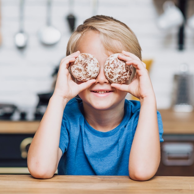 Ragazzino che copre i suoi occhi di biscotti