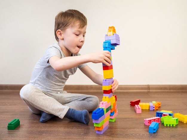 Ragazzino che gioca con il gioco colorato del blocco sul pavimento