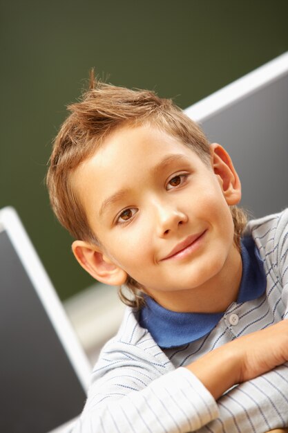 Ragazzino che si siede in aula e sorridente