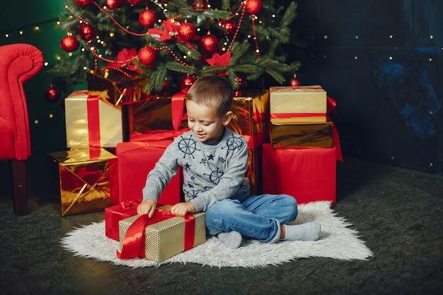 Ragazzino che si siede vicino all'albero di Natale