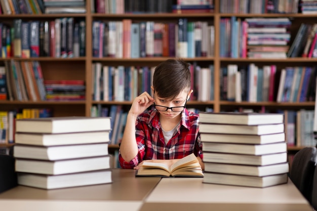 Ragazzino con gli occhiali in biblioteca