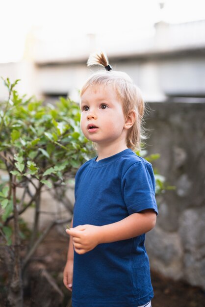 Ragazzino con la coda dei capelli che osserva via