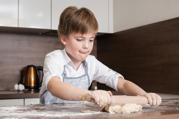 Ragazzino concentrato per arrotolare la pasta