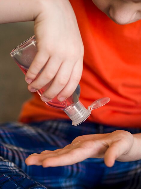 Ragazzino del primo piano che usando disinfettante per le mani
