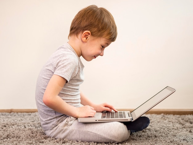 Ragazzino di vista laterale che gioca sul suo computer portatile