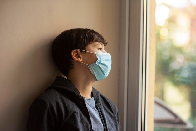 Ragazzino di vista laterale con mascherina medica che osserva via