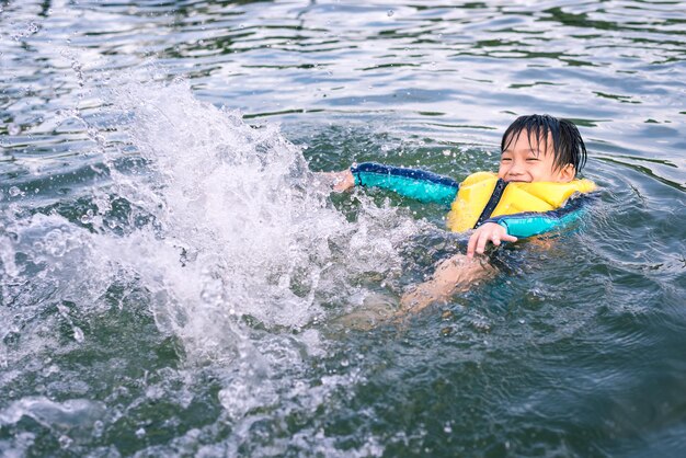 Ragazzino felice di nuotare e giocare nel concetto di sport e ricreazione del lago