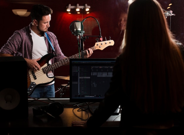 Ragazzo a suonare la chitarra e la donna registrando da dietro la vista