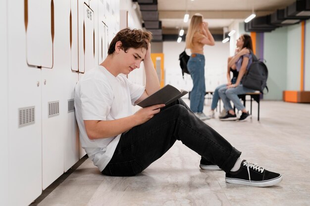 Ragazzo a tutto campo che legge sul pavimento