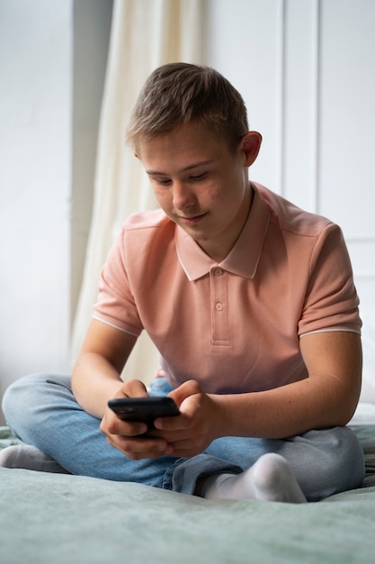 Ragazzo a tutto campo con sindrome di down che tiene il telefono