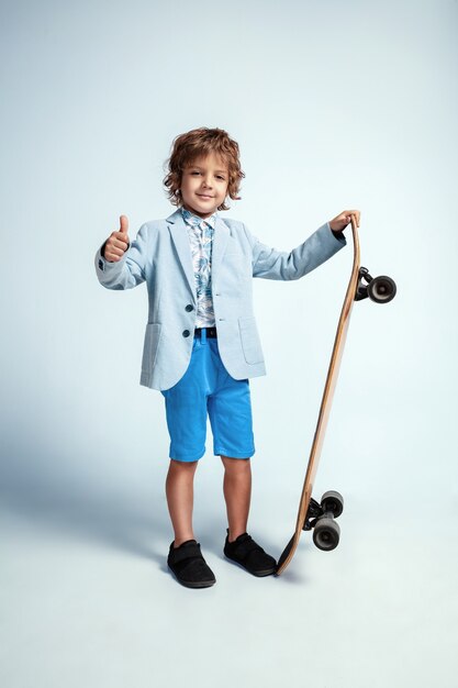 Ragazzo abbastanza giovane su skateboard in abbigliamento casual su studio bianco