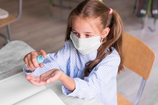 Ragazzo ad alto angolo che disinfetta le sue mani