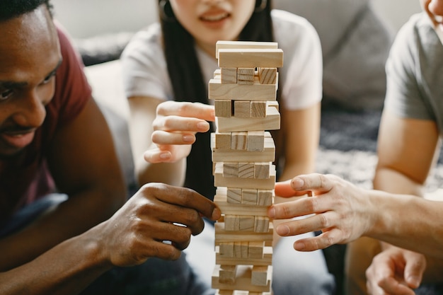 Ragazzo africano e coppia asiatica che giocano a jenga Gioca a un gioco da tavolo nel tempo libero Concentrati su un gioco