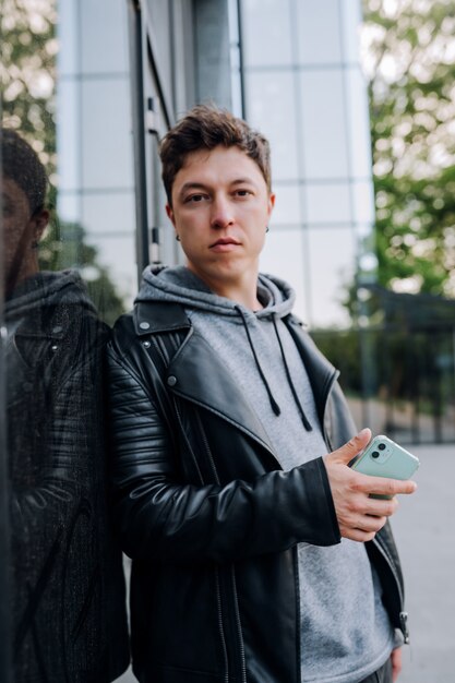 Ragazzo alla moda con lo smartphone in città.