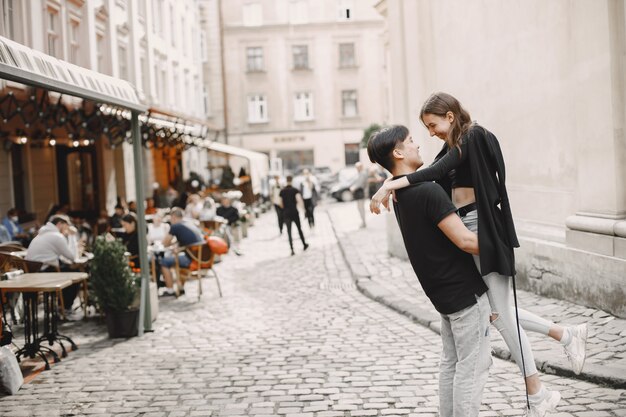 Ragazzo asiatico e la sua ragazza caucasica in abbigliamento casual in piedi sulla strada di Leopoli. Coppia che si abbraccia mentre cammina insieme in città
