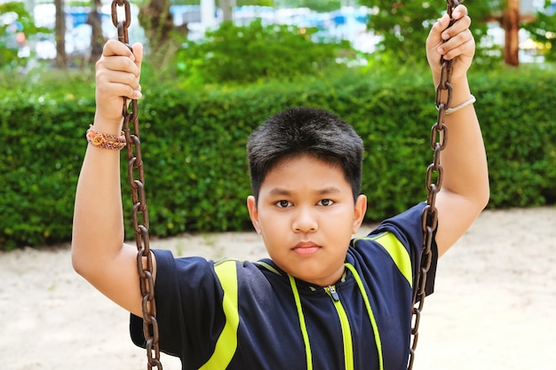 Ragazzo asiatico sportivo felice giocare sul parco giochi in giardinaggio.