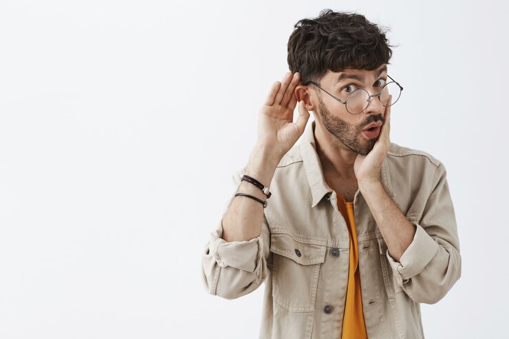 Foto gratuito ragazzo barbuto alla moda incuriosito che posa contro il muro bianco