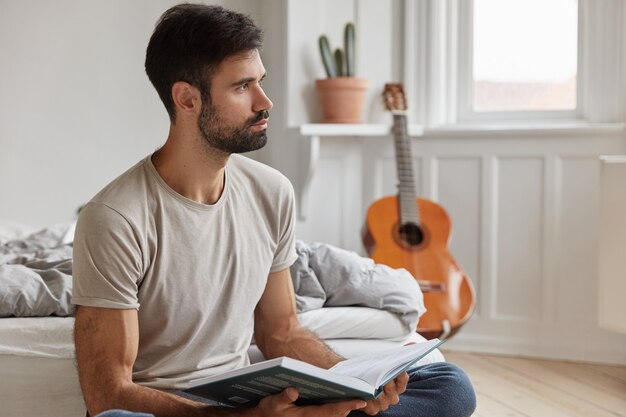 Ragazzo barbuto professionista intelligente in posa a casa mentre si lavora