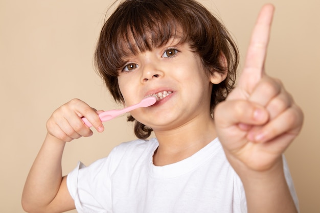 ragazzo carino adorabile lavarsi i denti sul rosa