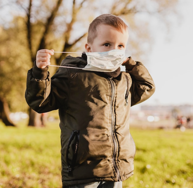 Ragazzo carino che indossa una maschera medica nel parco