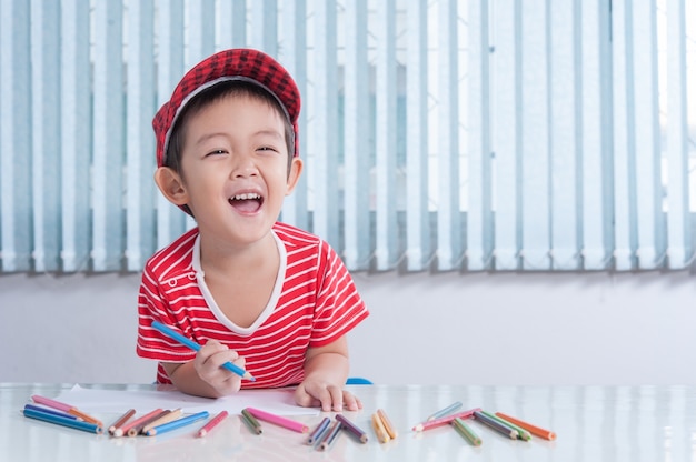 Ragazzo carino disegna con matite di colore nella stanza dei bambini