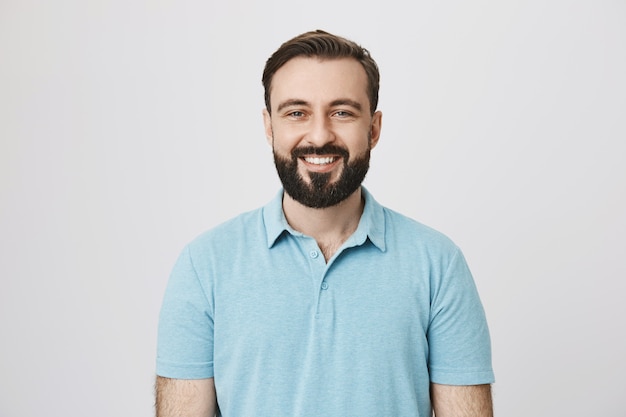 Ragazzo caucasico sorridente con la barba che sembra felice