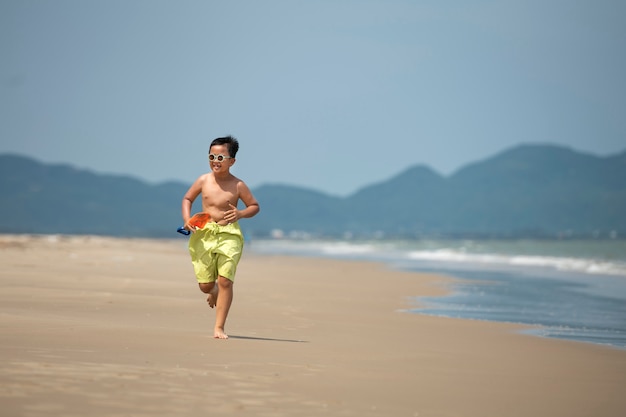 Ragazzo che corre sul colpo pieno della spiaggia