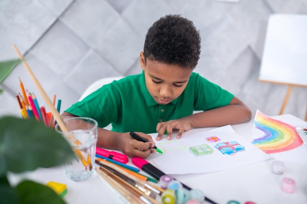 Ragazzo che disegna con pennarello colorato seduto al tavolo