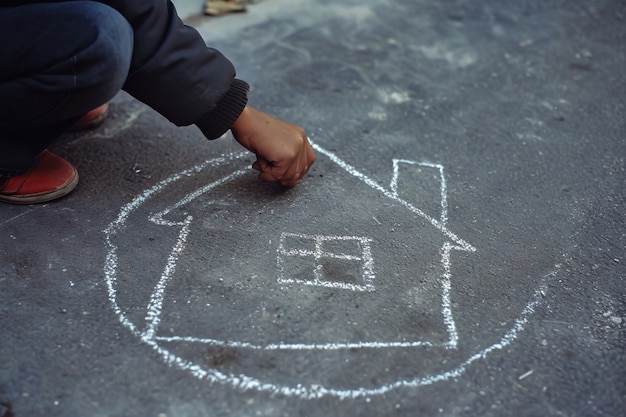 Ragazzo che disegna una casa con il gesso sul pavimento