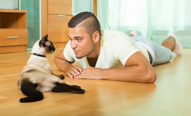 Ragazzo che gioca con il gattino siamese