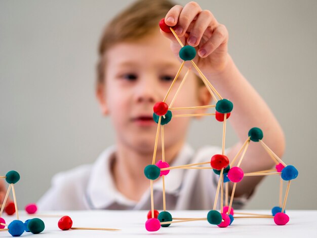 Ragazzo che gioca con il gioco colorato degli atomi sul tavolo