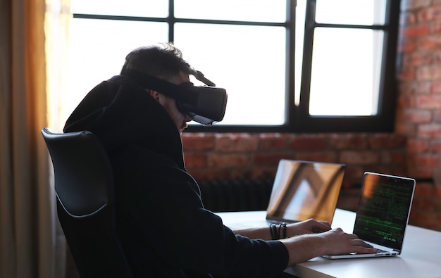 Ragazzo che gioca con la cuffia avricolare e il computer portatile di VR