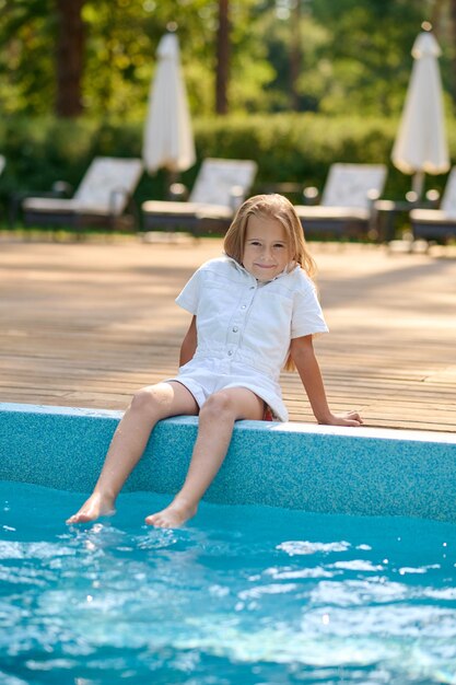 Ragazzo che gioca. Ragazza bionda sveglia che gioca vicino alla piscina