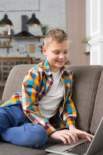 Ragazzo che per mezzo del computer portatile sul divano