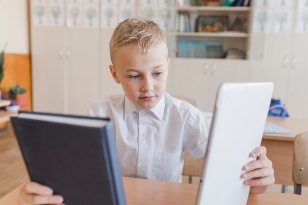 Ragazzo che sceglie tra libro e tablet a lezione