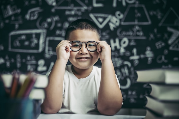 Ragazzo che studia e che tiene la gamba di occhiali in aula.