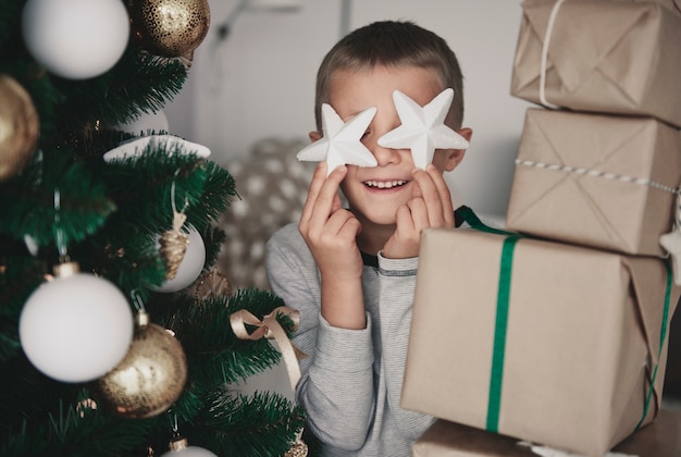 Ragazzo che tiene la decorazione di Natale davanti agli occhi