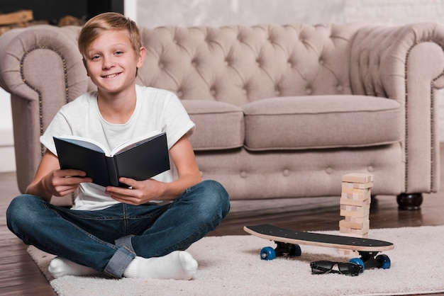 Ragazzo che tiene un libro e che si siede vicino ad uno strato